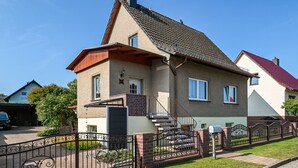 A two-story house with a red roof, a front door, and a staircase leading to the entrance. - Apartment 'Familie Perlik' with Wi-Fi (Röbel)