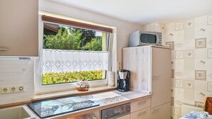 A compact kitchen with a window, a microwave, a coffee maker, and a sink. - Apartment 'Familie Perlik' with Wi-Fi (Röbel)