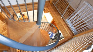 Eine Wendeltreppe mit Metallgeländern und Holzstufen, die zu einer oberen Etage führt.