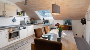 Eine moderne Küche mit Dachfenster, Holzboden und einem Essbereich mit Tisch und Stühlen.