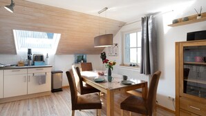 Eine moderne Küche mit Holzschränken, einem Esstisch mit Stühlen, einem Oberlicht und einem eingebauten Schrank mit Glastüren.