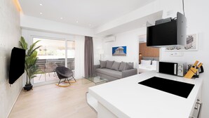A modern hotel room with a large bed, a sofa, a dining area, and a TV mounted on the wall. - Stylish 1-Bedroom in the center, 4mins walk to Syntagma Square (Athens)