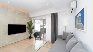 A modern living room with a flat-screen TV, a glass coffee table, a grey sofa, a potted plant, and a large window with curtains. - Stylish 1-Bedroom in the center, 4mins walk to Syntagma Square (Athens)