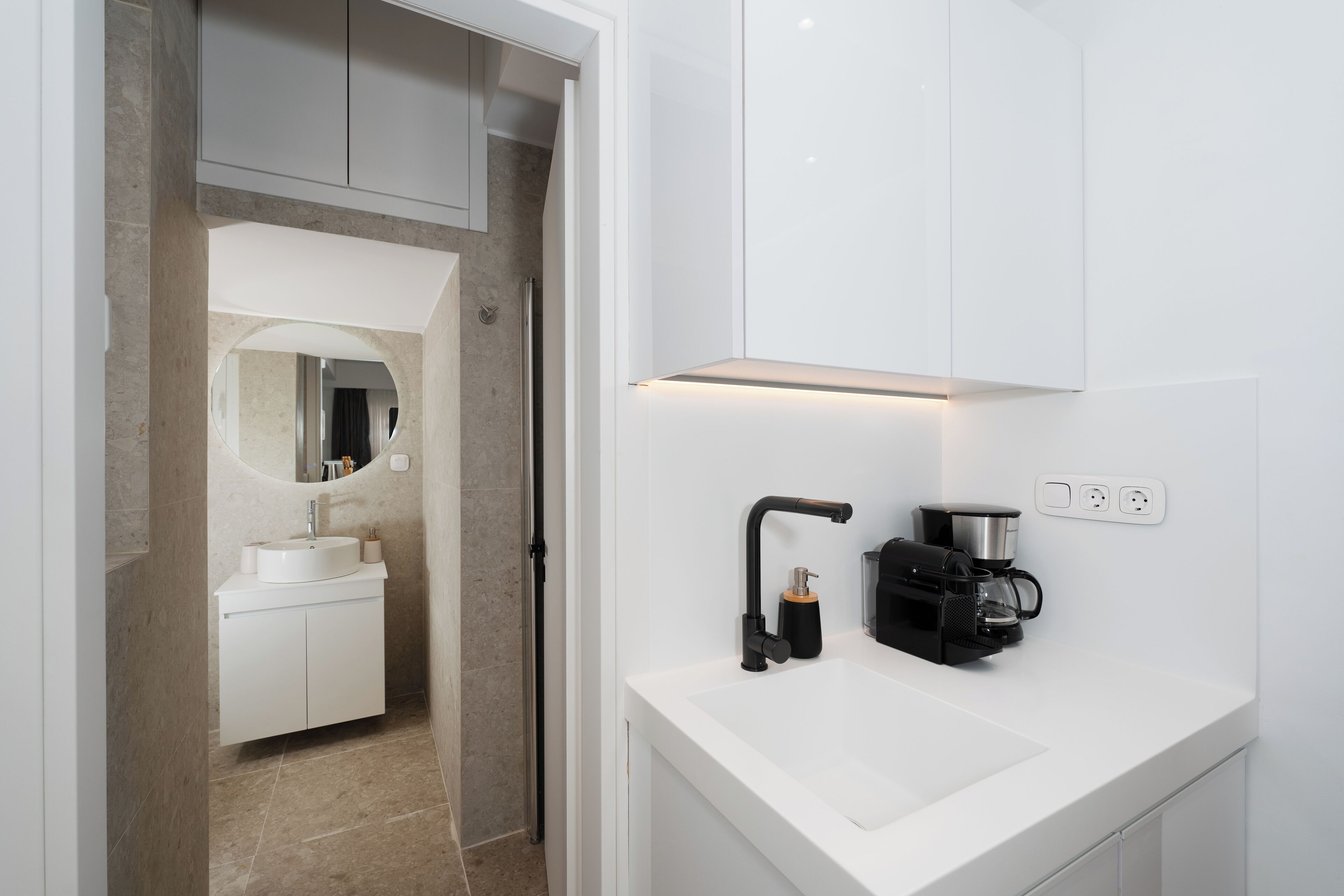 Une salle de bain moderne avec un lavabo blanc, un robinet noir et une machine à café.
