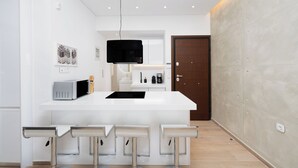 A modern kitchen with a white island, bar stools, a microwave, and a hanging light fixture. - Stylish 1-Bedroom in the center, 4mins walk to Syntagma Square (Athens)