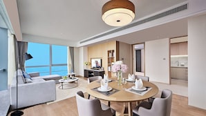 Ein modernes Hotelzimmer mit Essbereich, einer Wohnbereits mit Sofa und Meerblick.