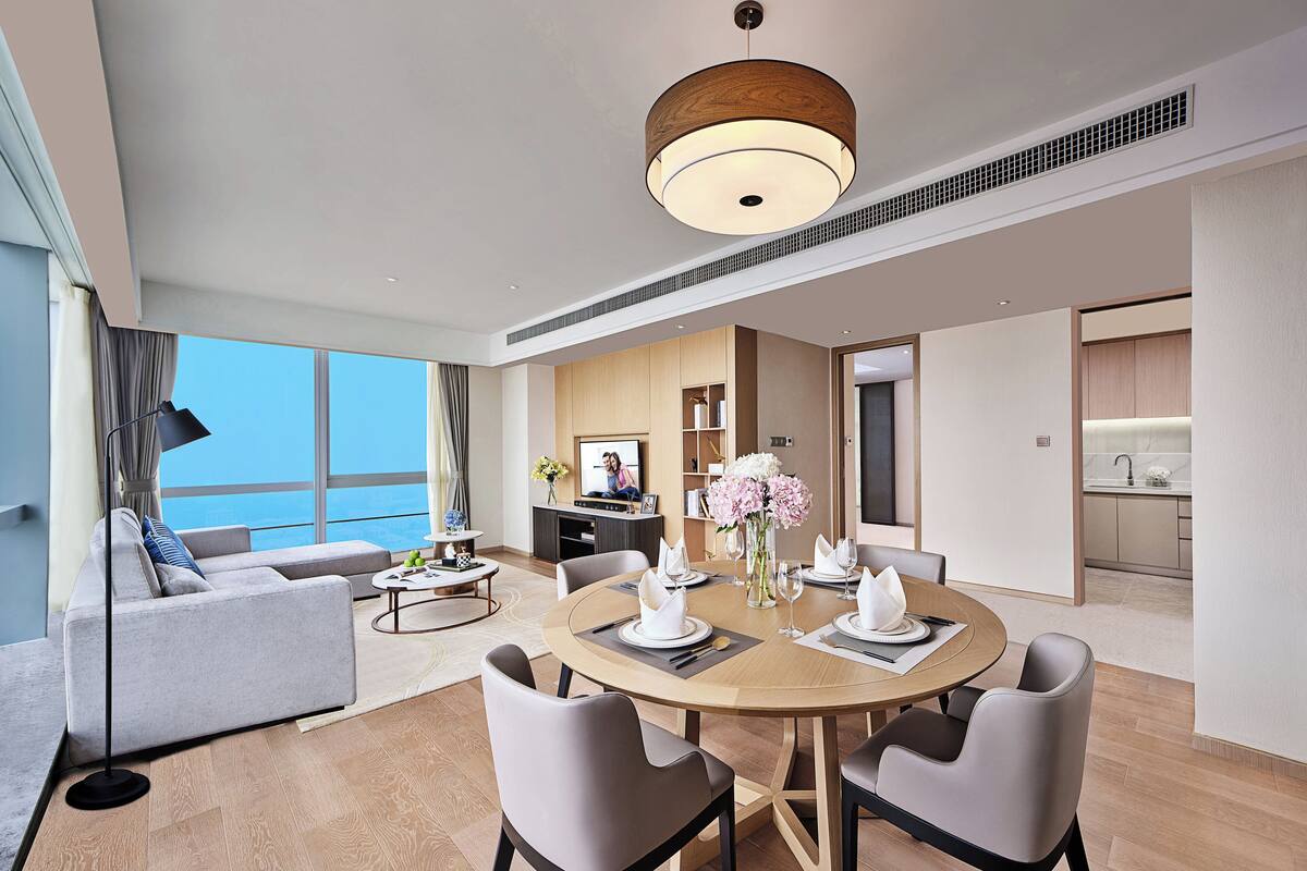 Ett modernt hotellrum med en matplats, ett vardagsrum med soffa och utsikt över havet.
