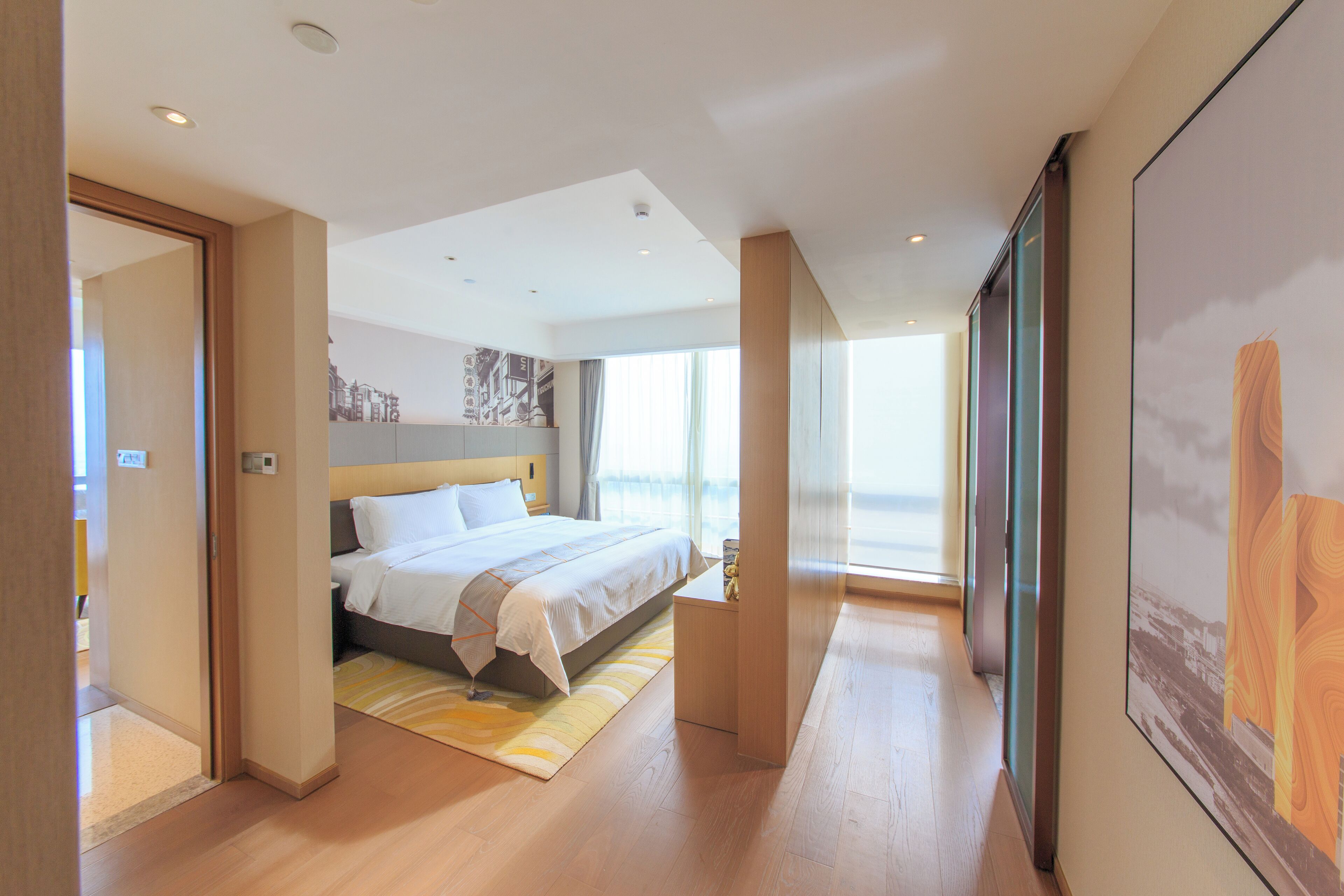 Ein modernes Hotelzimmer mit einem großen Bett, Holzboden und einem großen Fenster mit Blick.