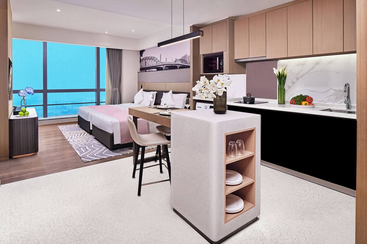 Ett modernt hotellrum med en stor säng, en matplats och ett kök.