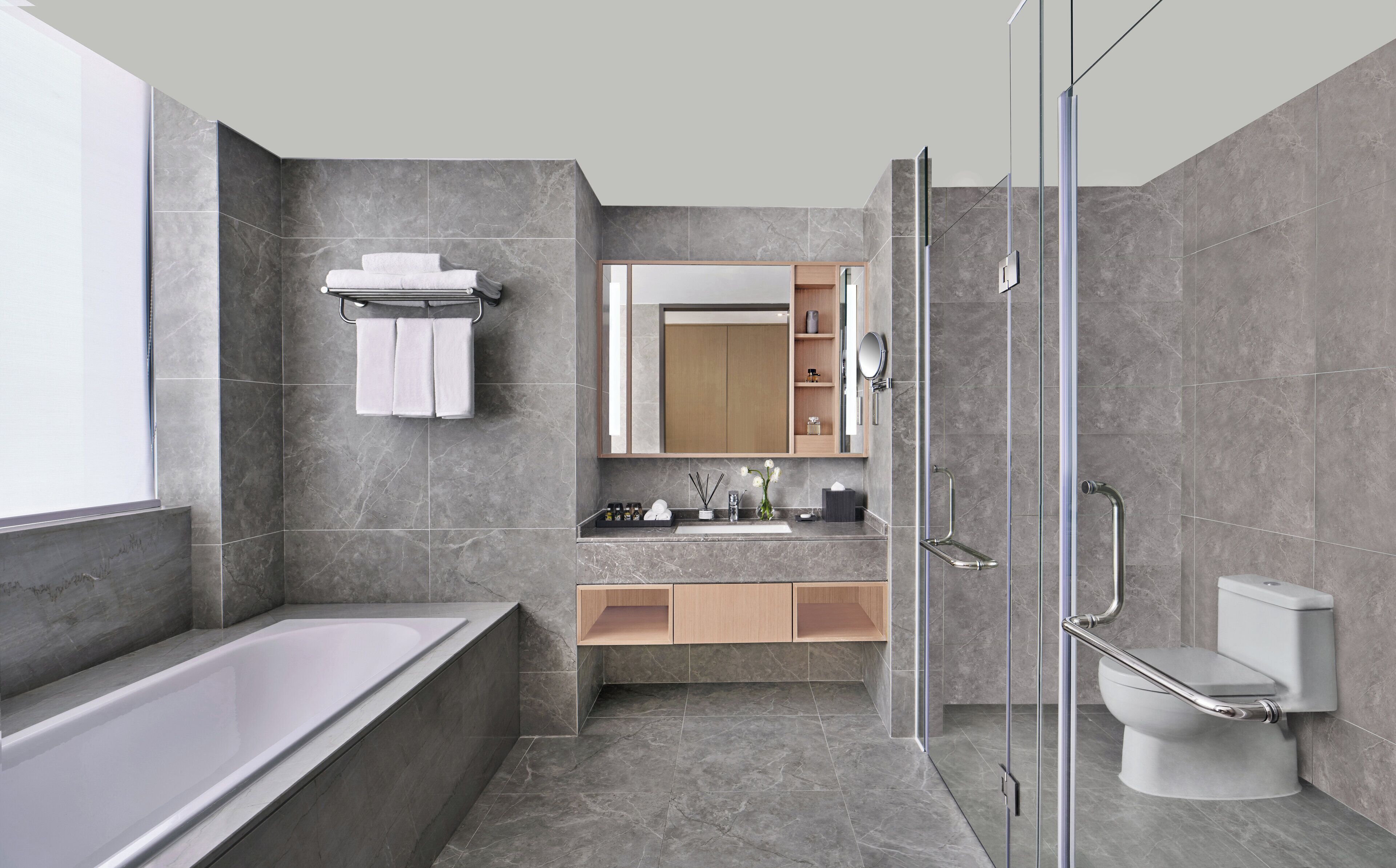 A modern bathroom with a bathtub, toilet, and glass shower enclosure.