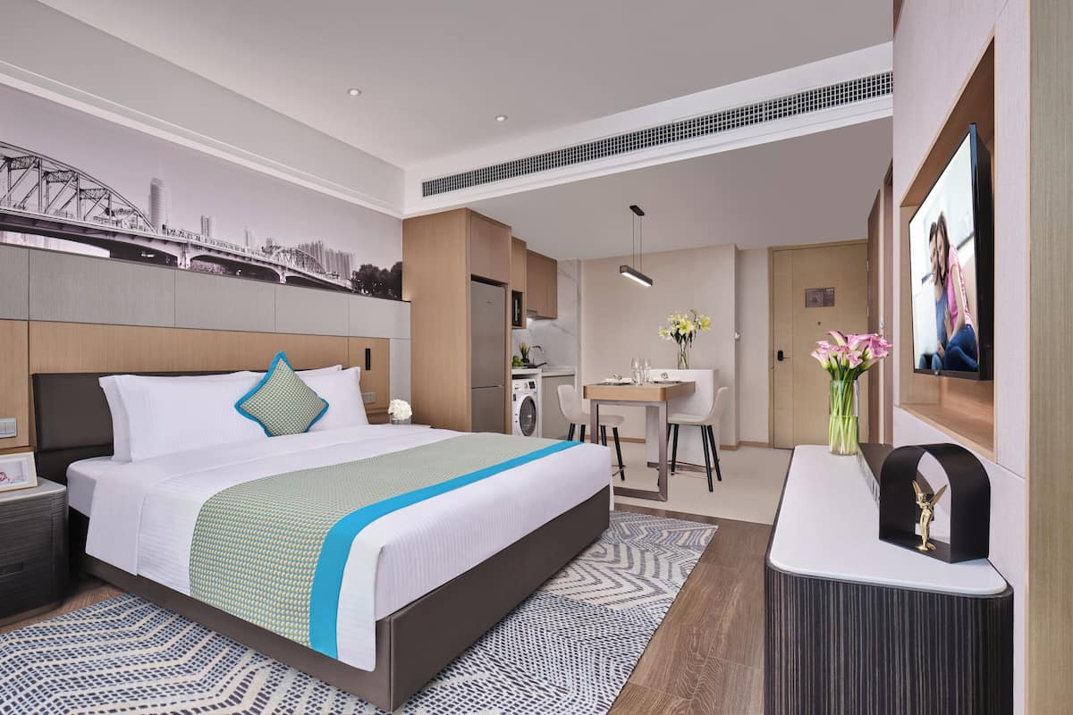 Ett modernt hotellrum med en stor säng, ett skrivbord, en tvättmaskin och en TV.