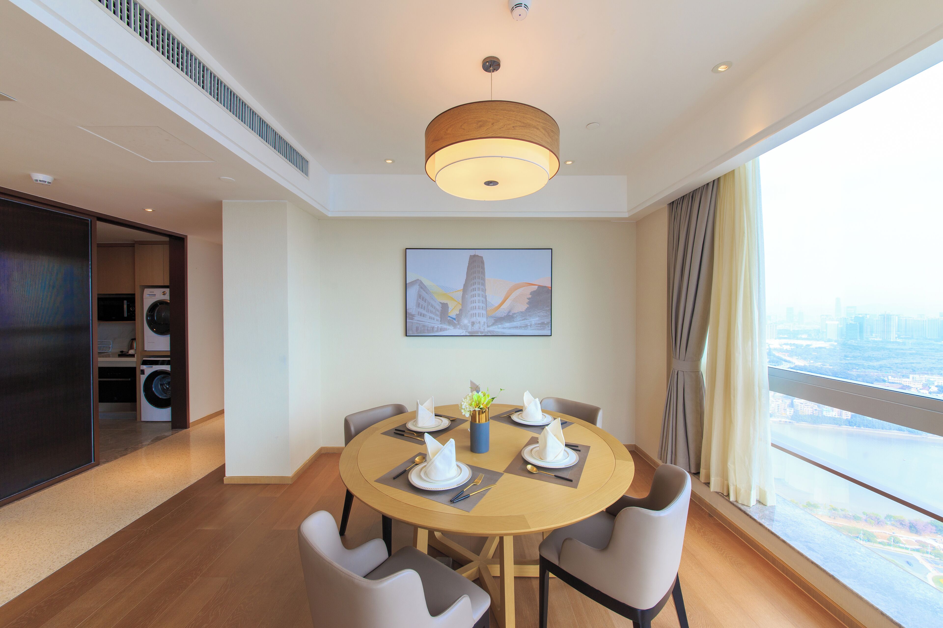 A modern dining area with a round table, chairs, and a ceiling light.