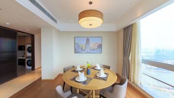A modern dining area with a round table, chairs, and a ceiling light.