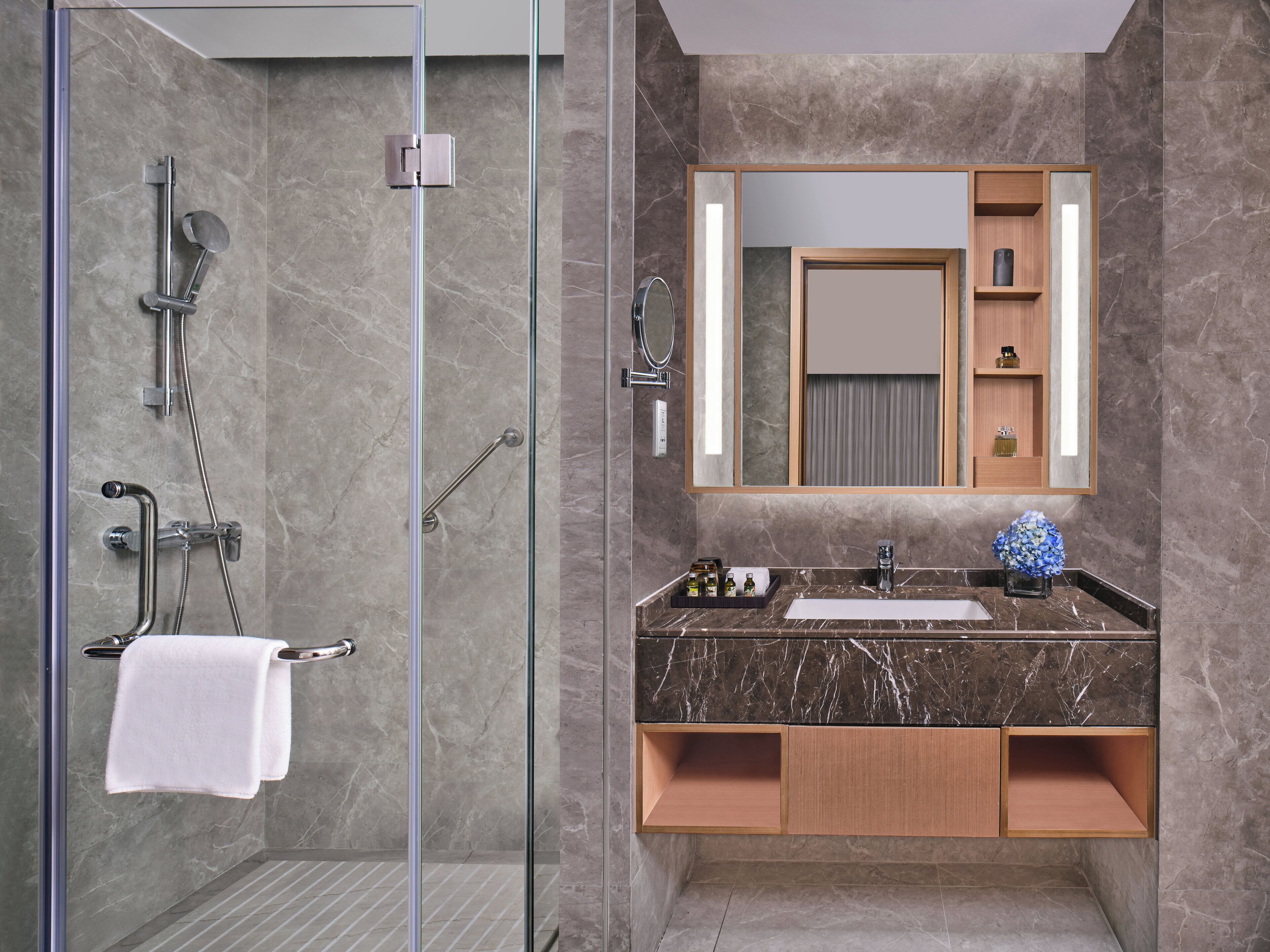 A modern bathroom with a glass-enclosed shower, a marble countertop, and a large mirror above the sink.
