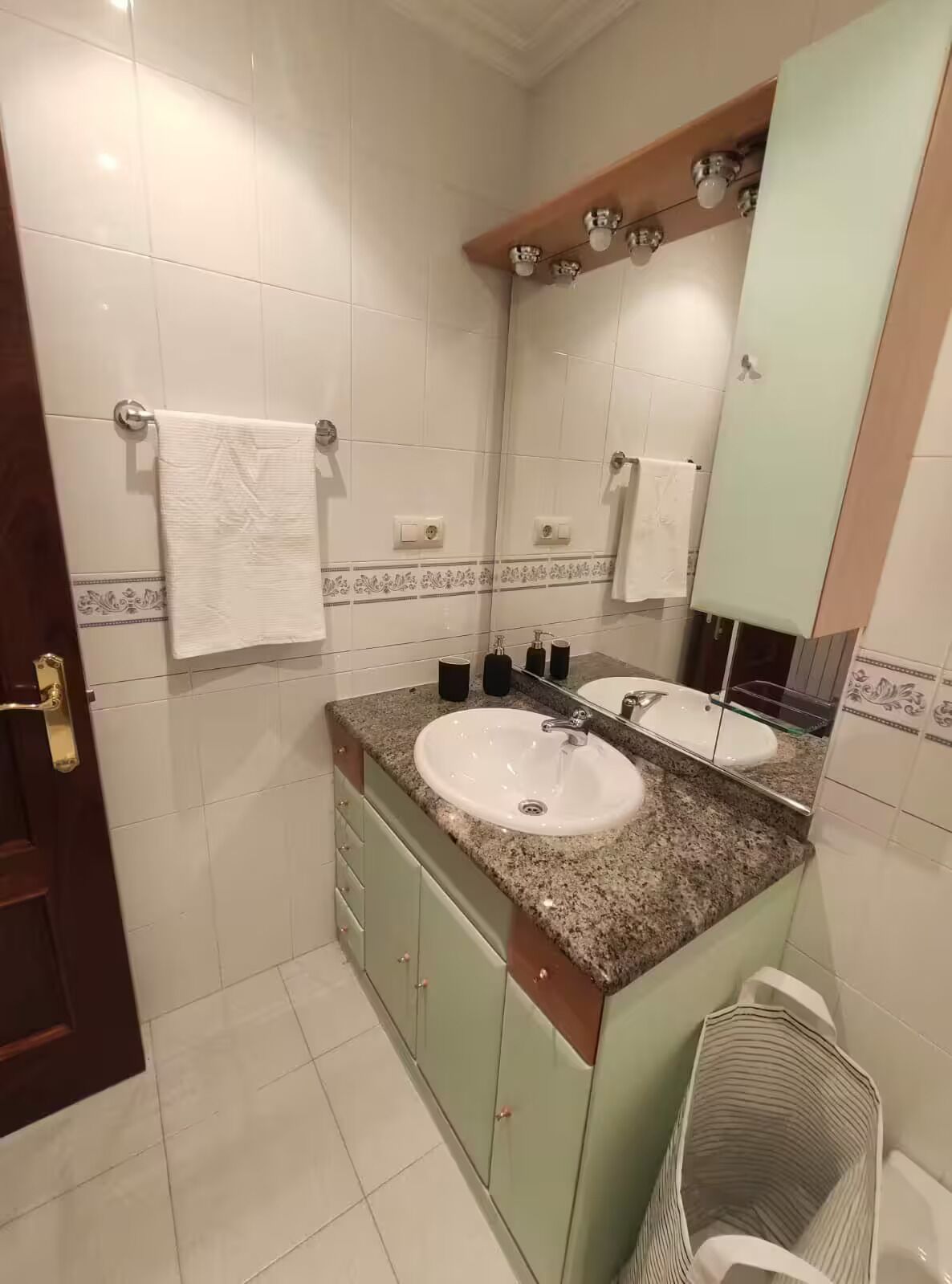 Une salle de bain avec deux lavabos, un grand miroir et un porte-serviettes.