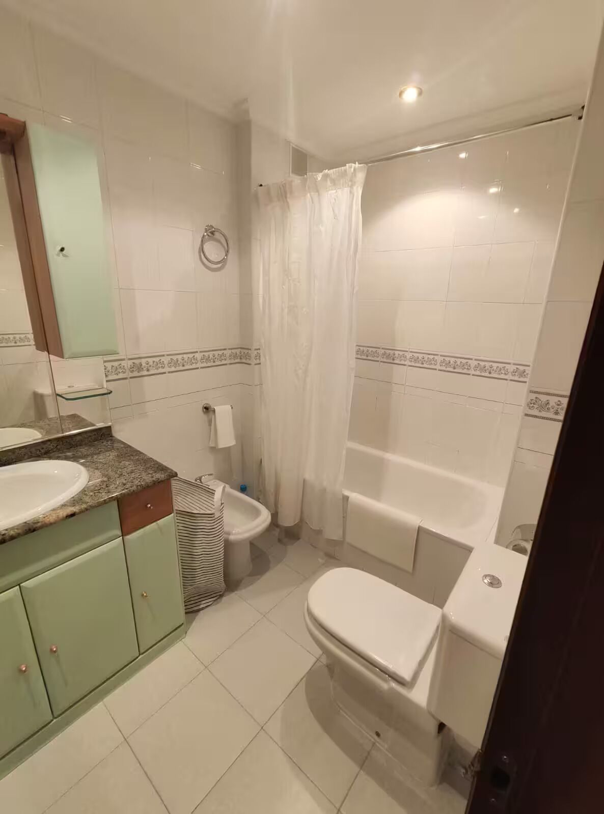 Een badkamer met wastafel, toilet, hygiëneschuimer en bad.