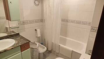 Een badkamer met wastafel, toilet, hygiëneschuimer en bad.
