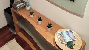 Une petite salle de bain bien rangée, avec un meuble-lavabo en bois, un miroir et une étagère contenant des articles de toilette et un livre.