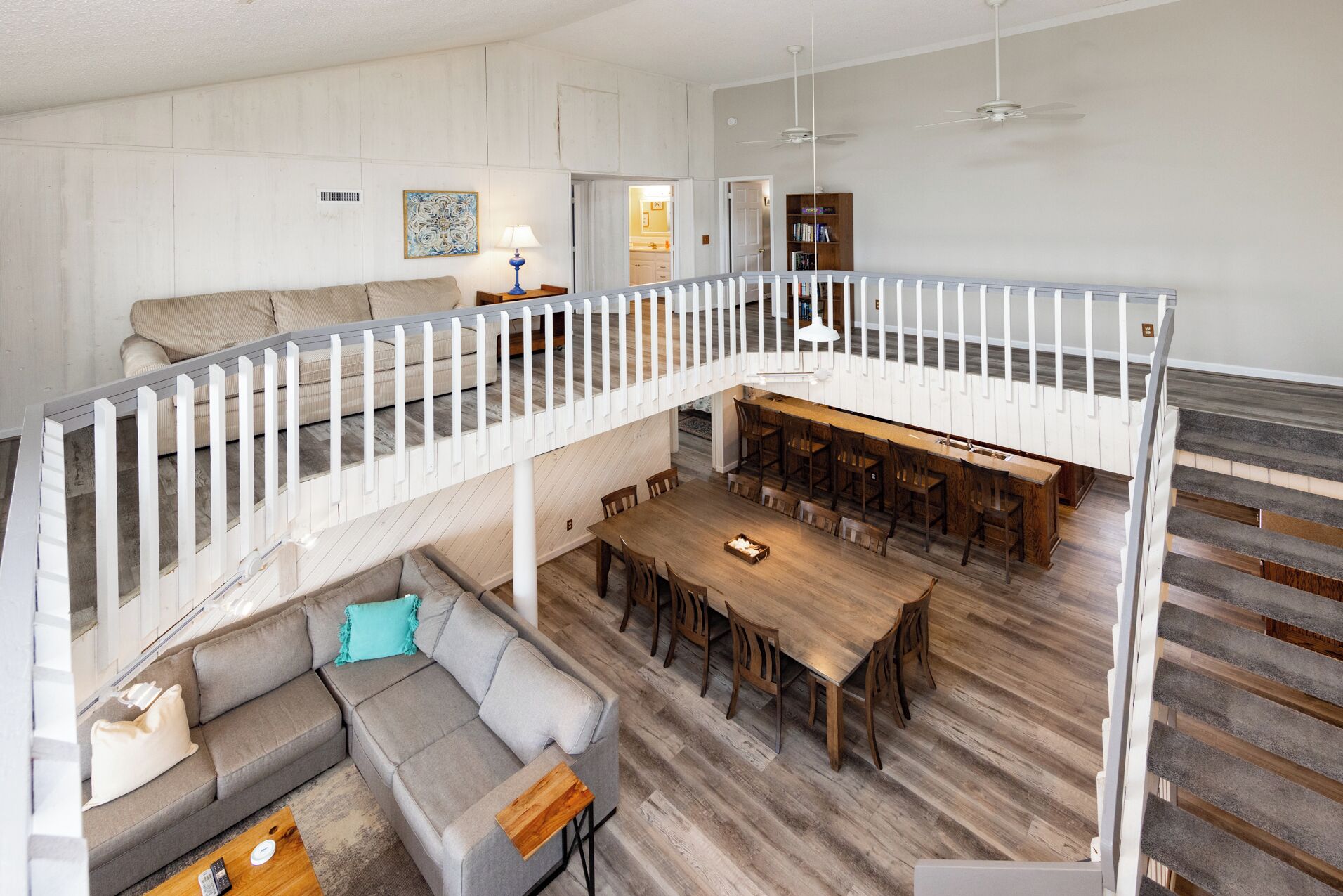 A spacious loft with a dining area, a sofa, and a staircase.