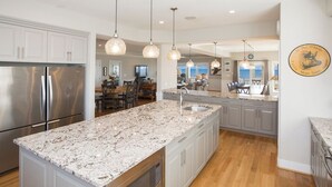 A modern kitchen with granite countertops, stainless steel appliances, and pendant lighting.