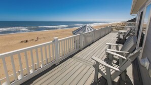 A wooden deck with white railings overlooking a beach.
