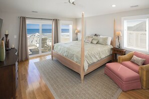 Relax in this serene bedroom with a four-poster bed, chaise lounge, and ocean views.