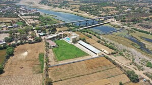 Vue aérienne d’une zone rurale avec un pont, des champs et un grand bâtiment doté d’une piscine.