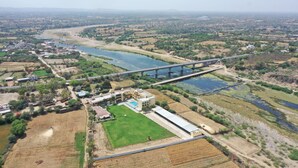 Une vue aérienne d’une ville avec un pont imposant, des champs verdoyants et un grand bâtiment doté d’une piscine.