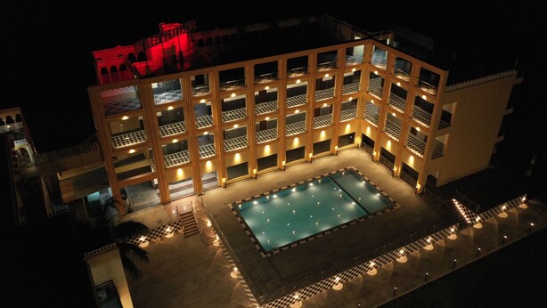 Un hôtel à plusieurs étages doté d’un espace piscine, avec un sol à motifs en damier et de nombreux balcons.