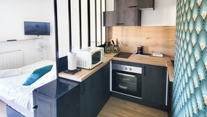 A compact kitchen with a microwave, oven, and wooden countertop.