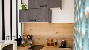 A modern kitchen with dark cabinetry, a microwave, a stove, and a unique ceiling light fixture.