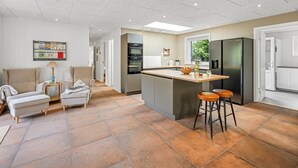 A modern kitchen with a central island, a dining area with a sofa and chairs, and a living room with a sofa and a coffee table. - "Baggi" - 900m from the sea by Interhome (Blåvand)