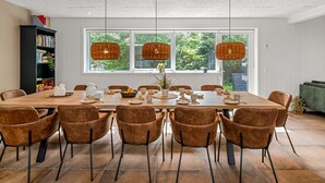 A dining area with a large table, brown upholstered chairs, and hanging wicker lamps. - "Baggi" - 900m from the sea by Interhome (Blåvand)
