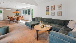 A spacious living area with a large sectional sofa, a round coffee table, and a dining area with a table and chairs. - "Baggi" - 900m from the sea by Interhome (Blåvand)