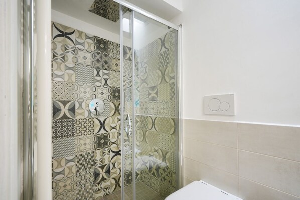 A shower with patterned tiles, a glass door, and a control panel on the wall. - Cozy apartment equipped with all comforts to accommodate up to 4 people, located on the ground floor of a complex of trulli with typical and evocative architecture. The accommodation is located in an enviable position: just 10 minutes from the historic c (Martina Franca)