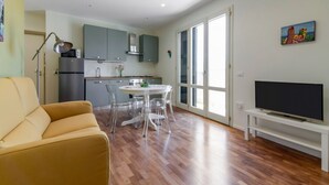 A modern apartment with a dining area, kitchen, sofa, TV, and large windows. - GuestHost - Palermo's Rooftop - Apt with Panoramic Terrace (Palermo)