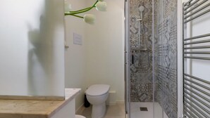 A bathroom with a toilet, a shower with a glass door, and a towel rack. - GuestHost - Palermo's Rooftop - Apt with Panoramic Terrace (Palermo)
