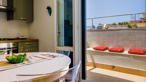A kitchen with a dining area, a view of the cityscape, and a balcony with red towels. - GuestHost - Palermo's Rooftop - Apt with Panoramic Terrace (Palermo)