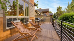 Eine Holzterrasse mit Liegestühlen, einem Grill und einem überdachten Patio.