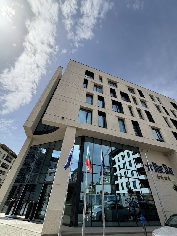 Ein modernes Gebäude mit Glastür, Flaggen und dem Blue Star Logo.