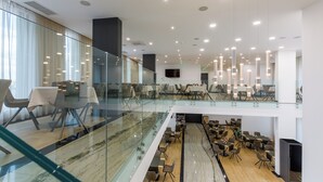 A modern hotel lobby with glass railings, multiple dining areas, and a central seating arrangement. - Blue Star Luxury Hotel (Sofia)