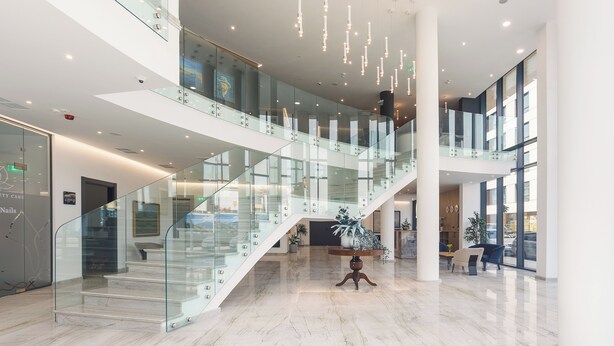 A spacious lobby with a glass staircase, marble flooring, and modern lighting fixtures. - Blue Star Luxury Hotel (Sofia)