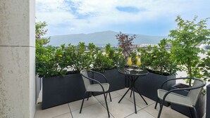 A balcony with two chairs and a table, overlooking a cityscape and a mountain. - Blue Star Luxury Hotel (Sofia)