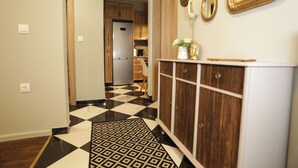 A hallway with a checkered floor, wooden cabinets, and a white console table with decorative items.