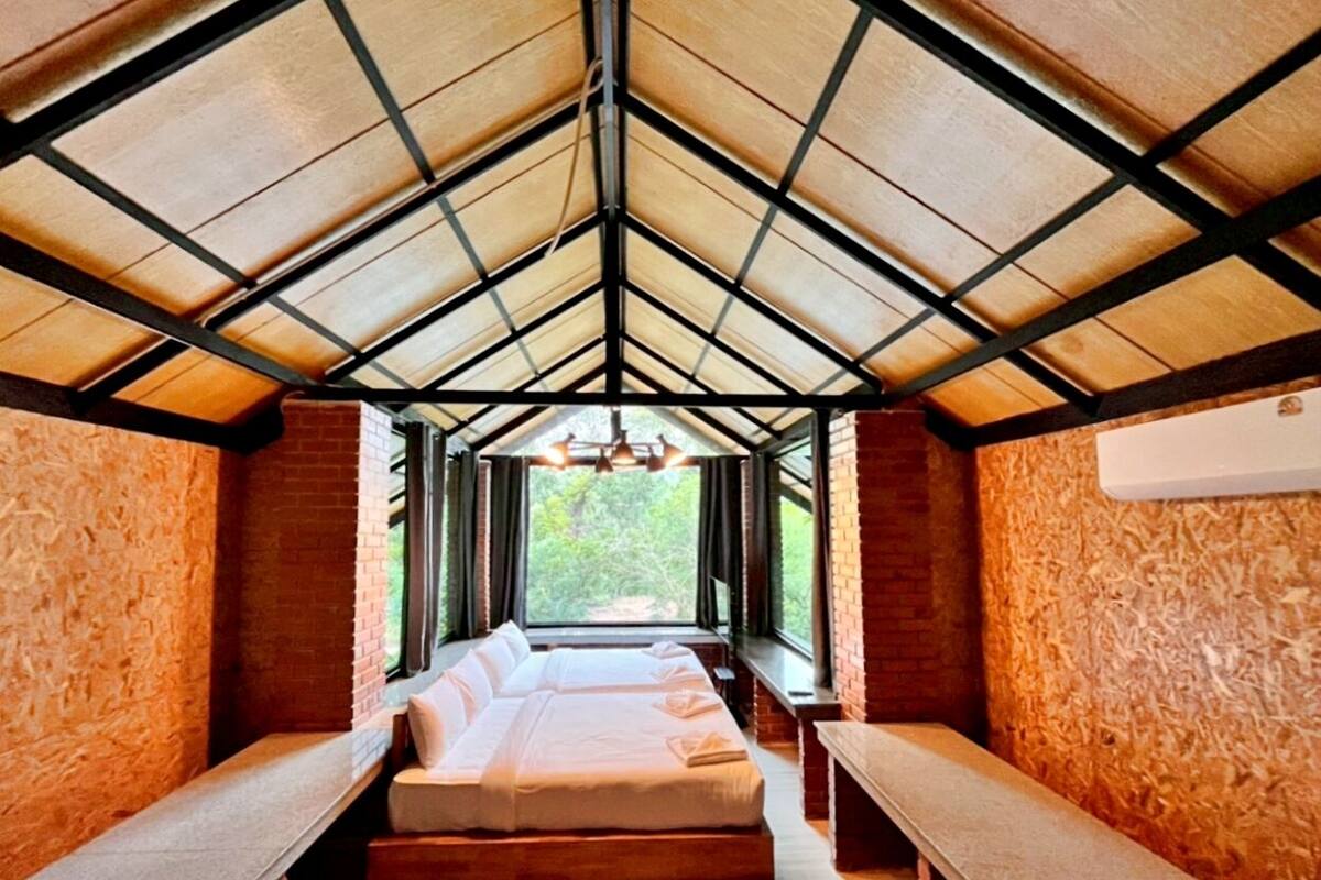 A room with a sloped ceiling, a bed, and a window.