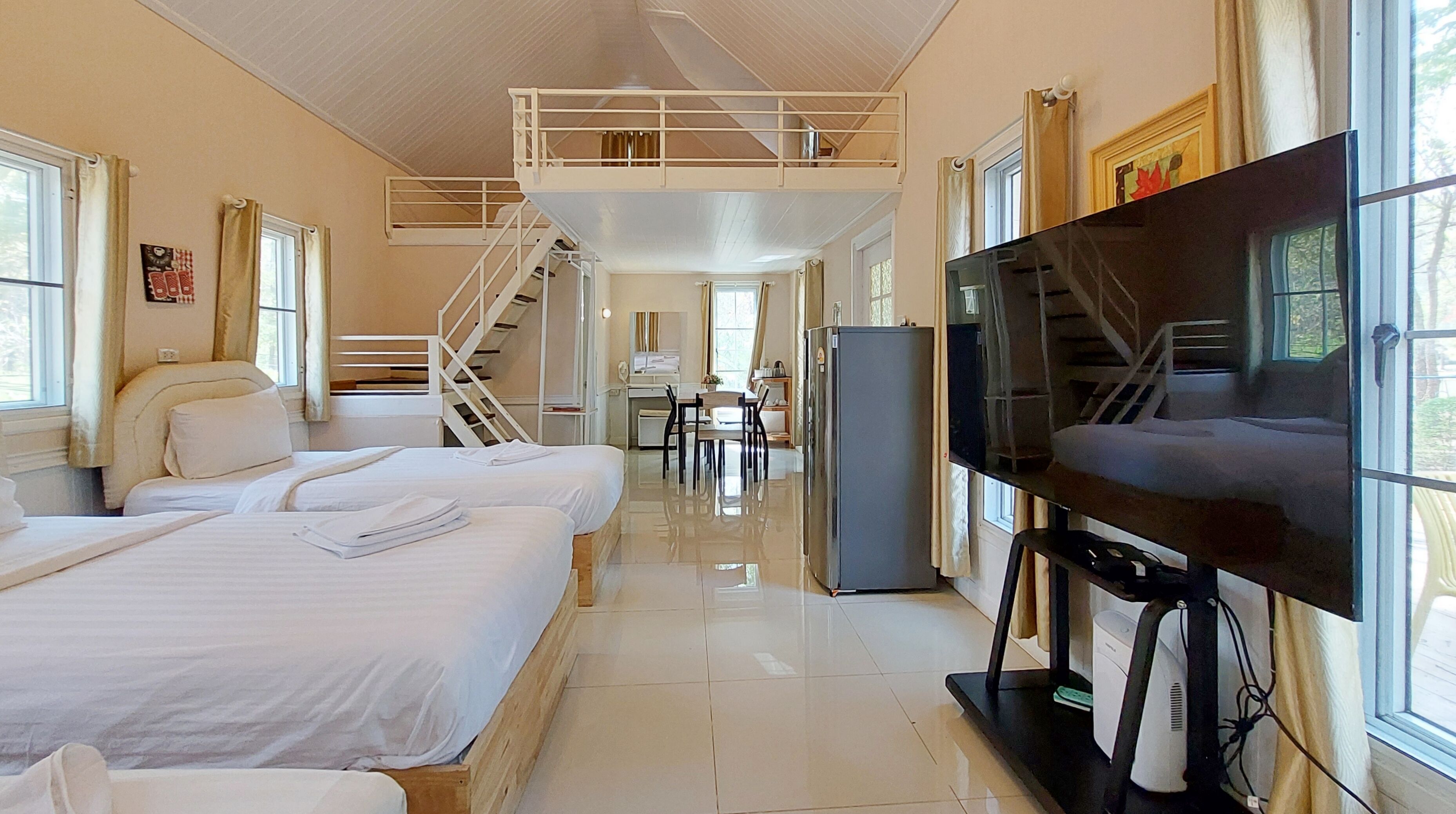 Une chambre d’hôtel avec deux lits, une télévision, un bureau et un escalier.