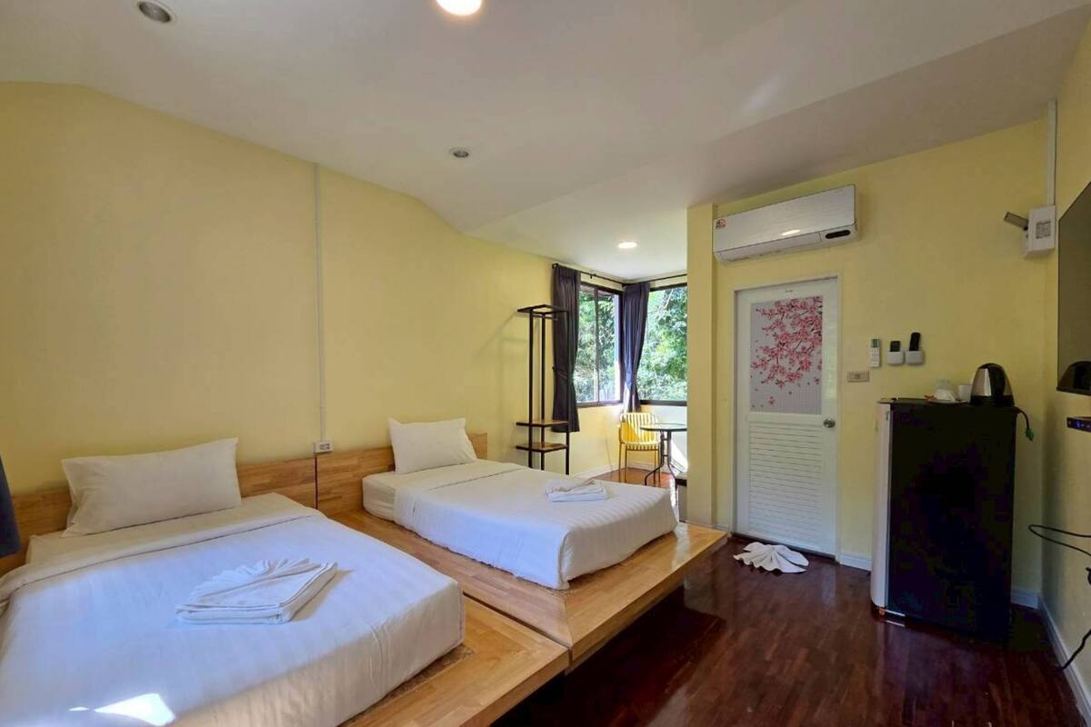 A hotel room with two beds, a wooden bench, a small table, and a radiator.