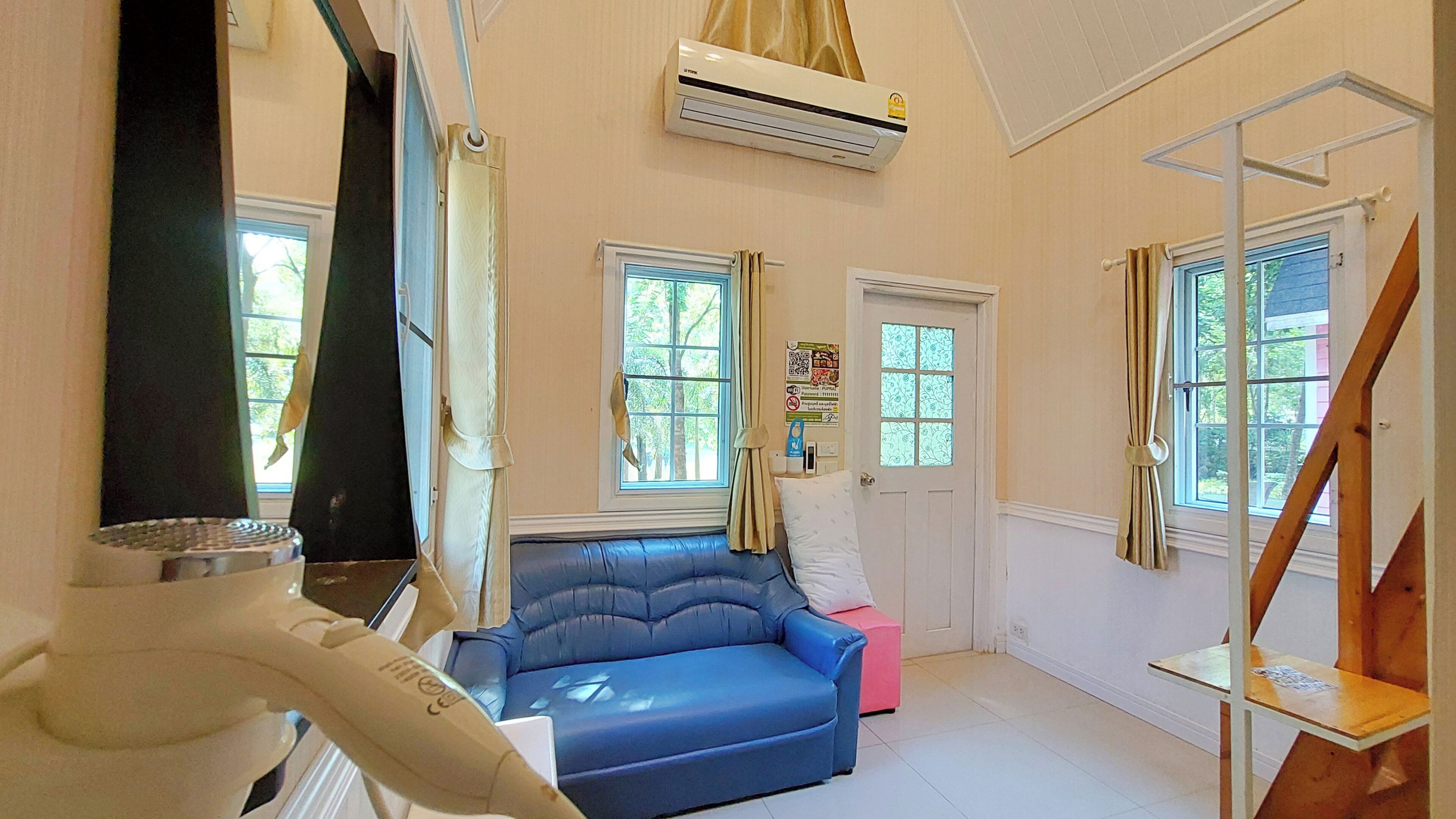 A room with a blue sofa, a pink chair, a wooden staircase, and a white door.