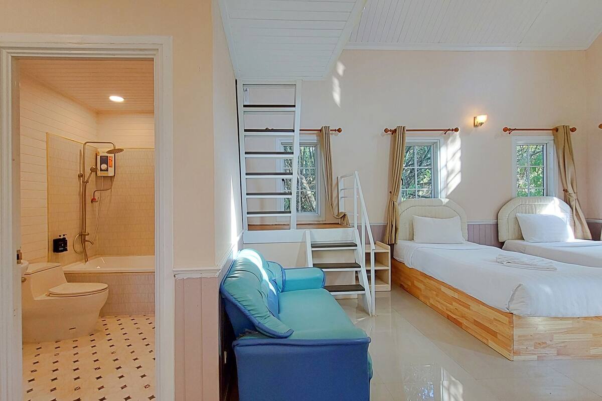A bedroom with a bed, a bathroom with a shower, and a seating area.
