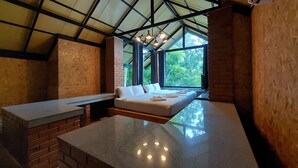 Ein Zimmer mit einem Bett, einem Tisch und Blick auf Grün.